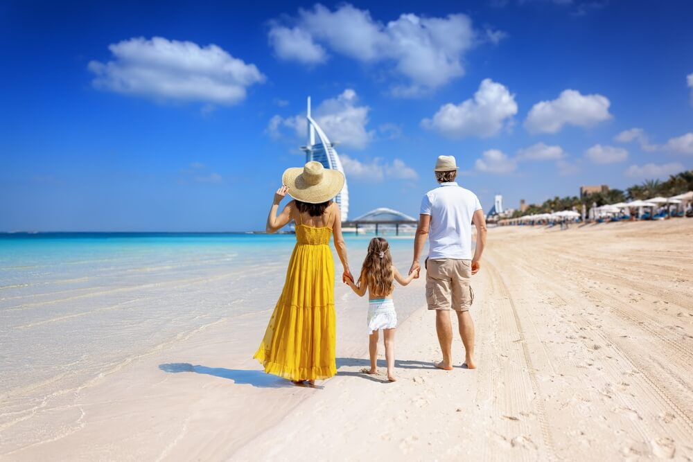 Turistická rodina na prechádzke po krásnej mestskej pláži